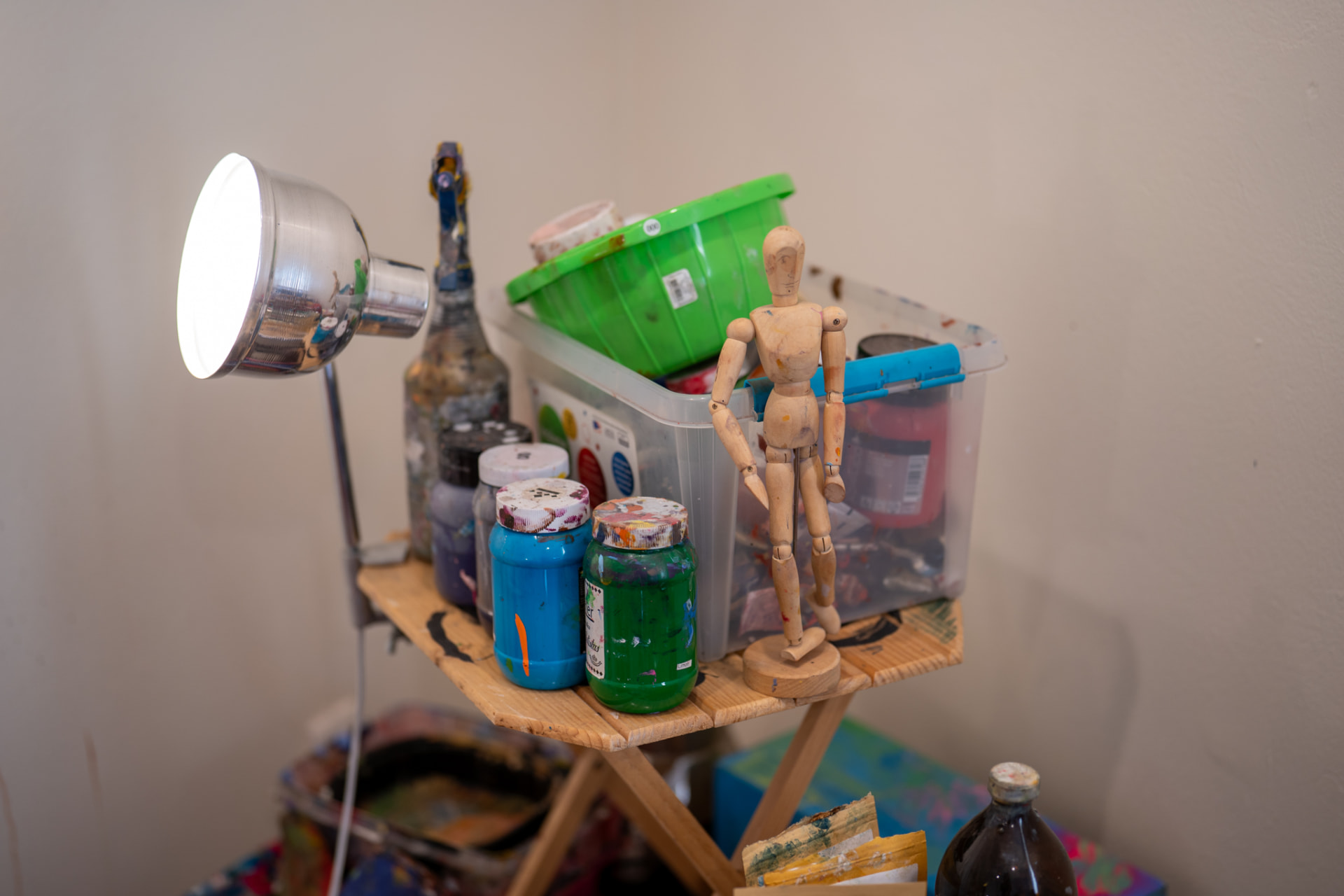 Mesa con pinturas y maniquí de madera en el estudio